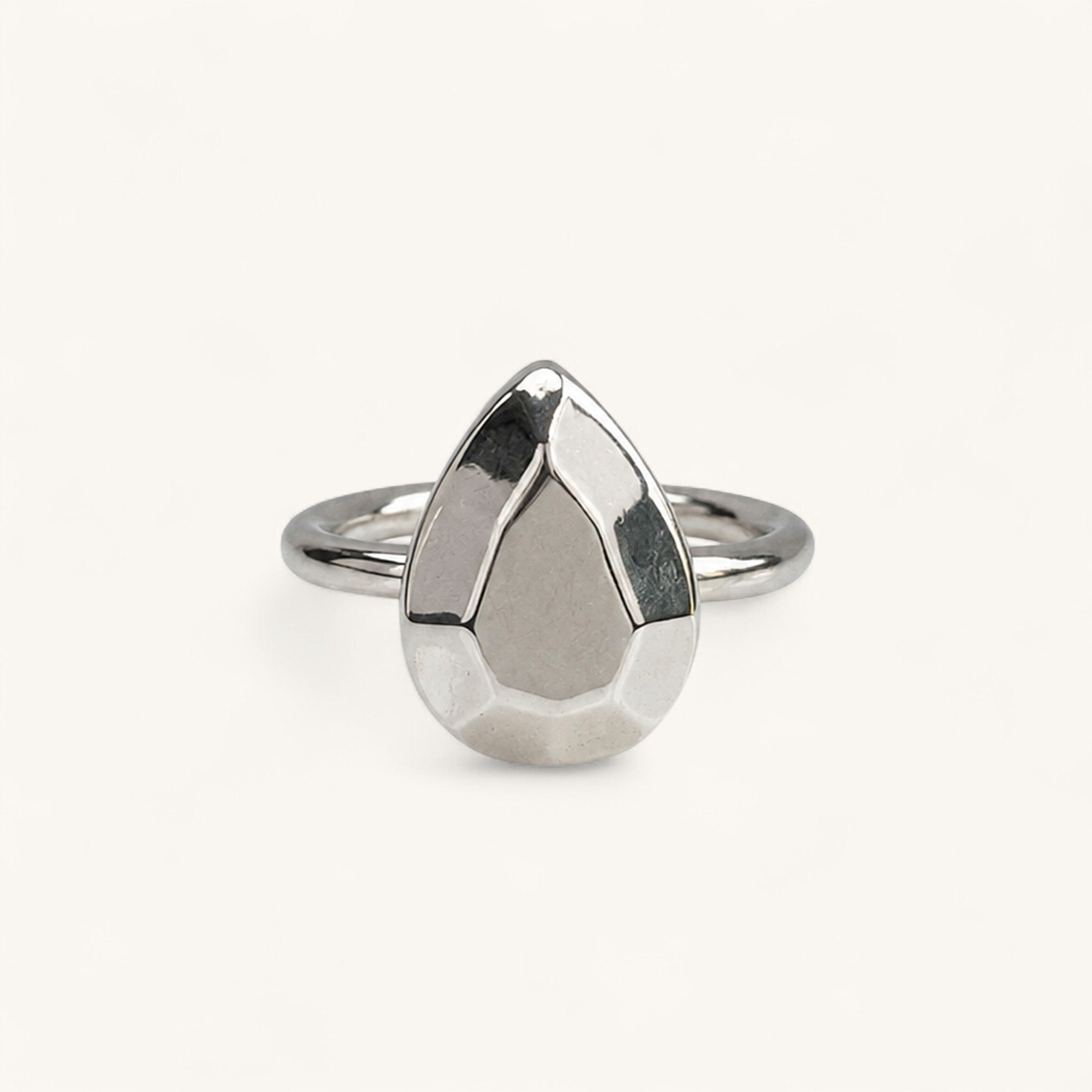 A silver ring featuring a faceted, pear-shaped metal top, handmade in London by Jennifer Loiselle 