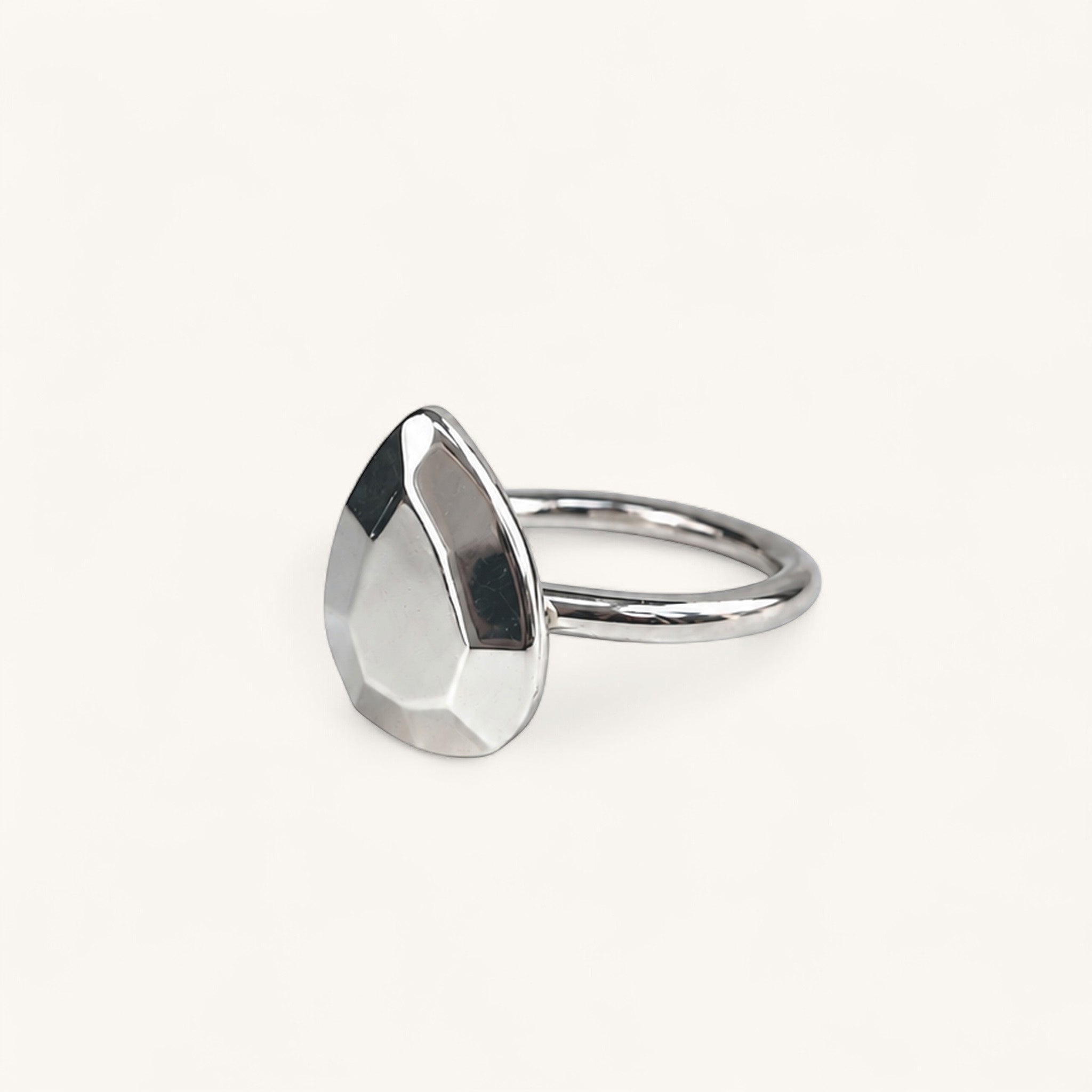 A silver ring featuring a faceted, pear-shaped metal top, handmade in London by Jennifer Loiselle 