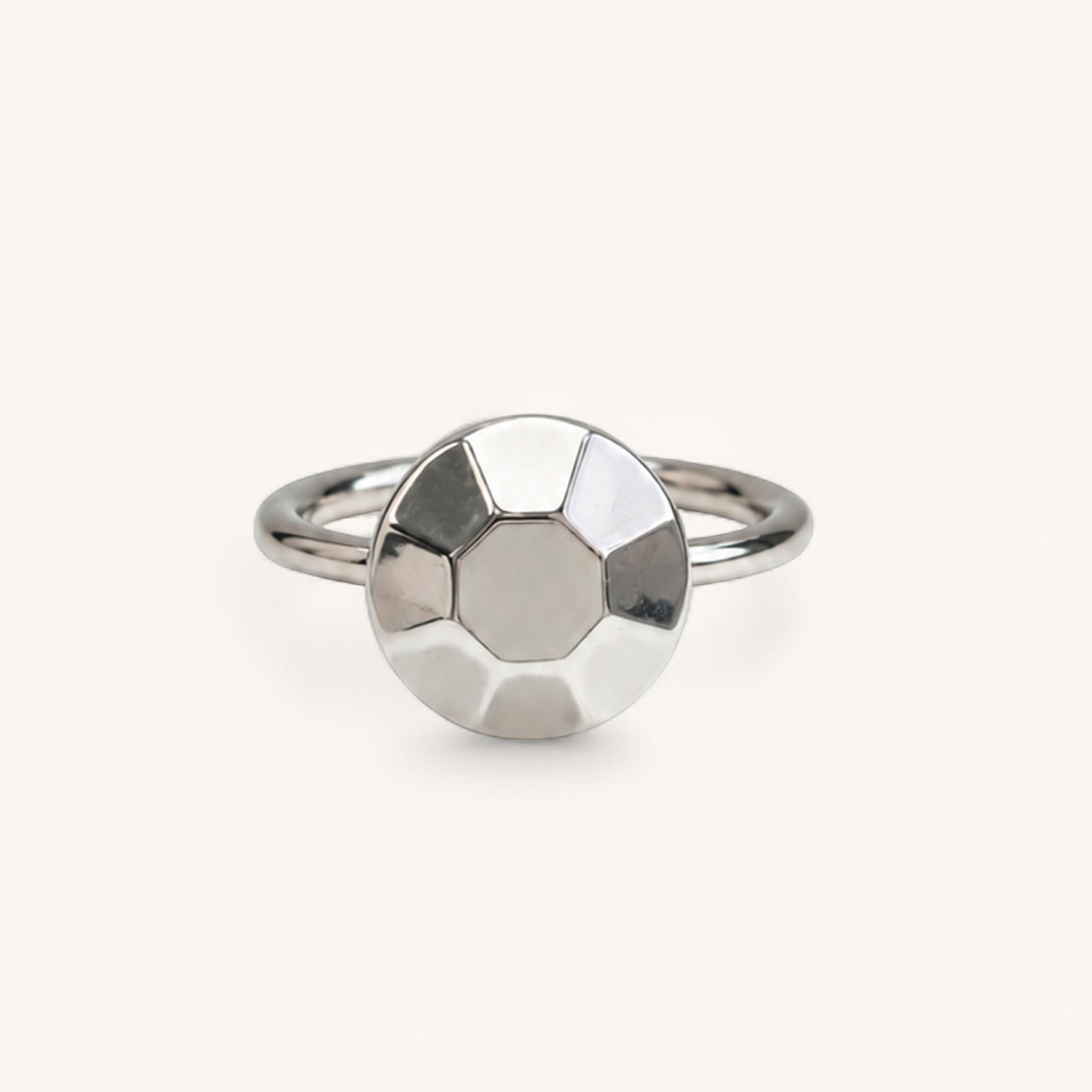 A silver ring featuring a circular, faceted geometric design on the front, handmade in London by Jennifer Loiselle