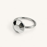 A silver ring featuring a circular, faceted geometric design on the front, handmade in London by Jennifer Loiselle