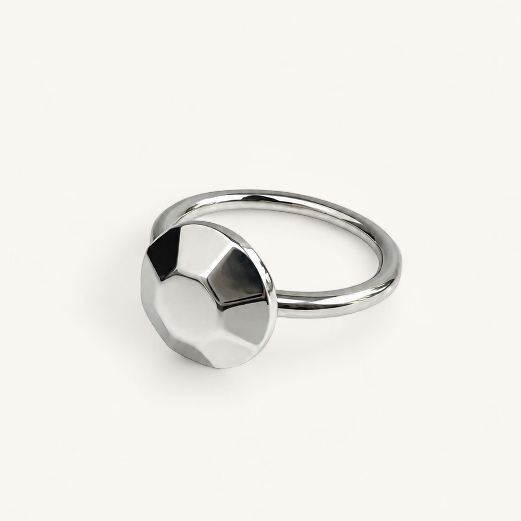 A silver ring featuring a circular, faceted geometric design on the front, handmade in London by Jennifer Loiselle