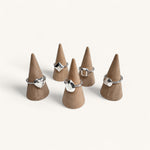Five silver rings shaped like gemstones on jewellery cones by Jennifer Loiselle