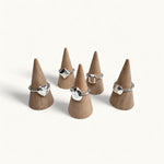 Five silver rings shaped like gemstones on jewellery cones by Jennifer Loiselle