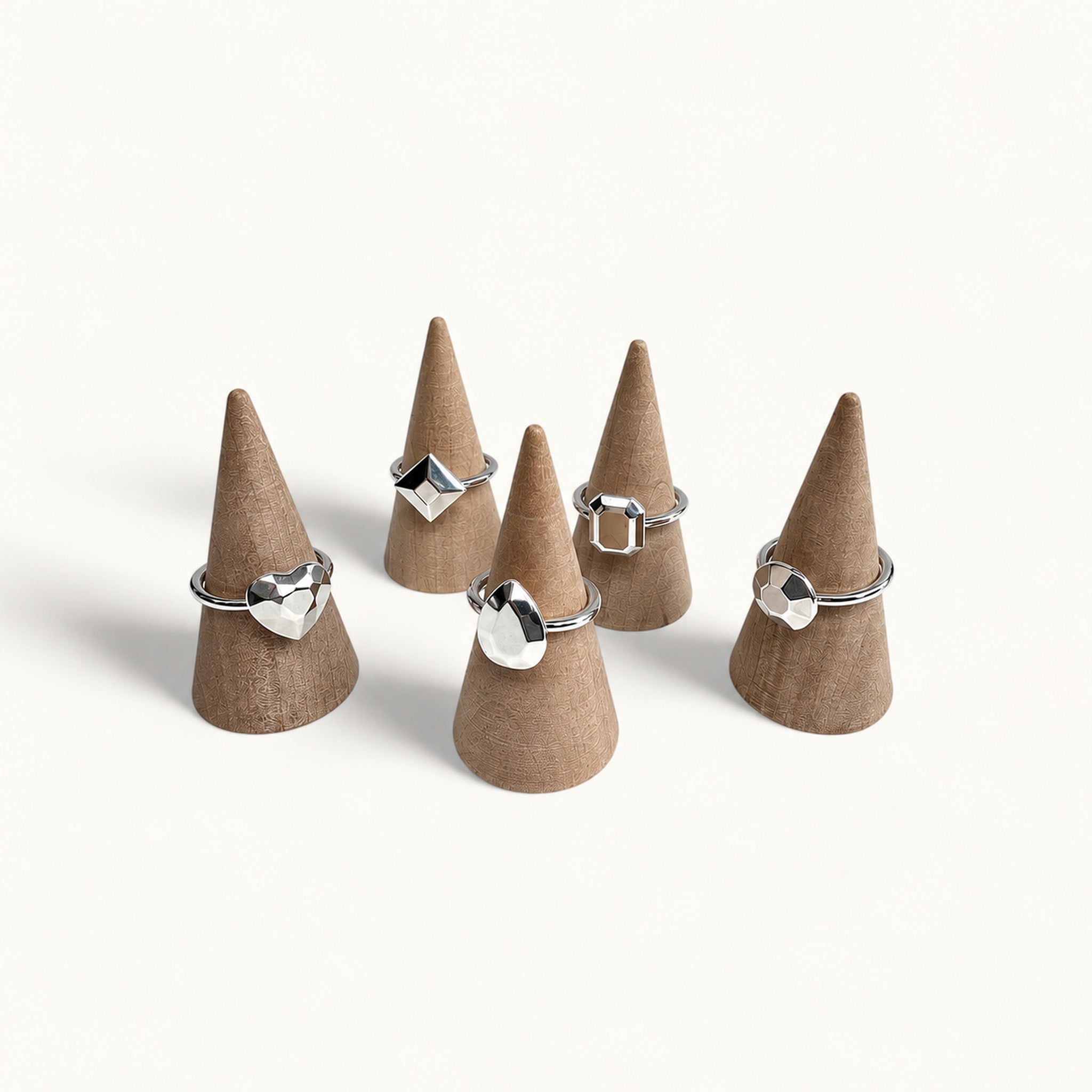 Five silver rings shaped like gemstones on jewellery cones by Jennifer Loiselle