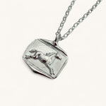 Silver pendant with horse design on a white background