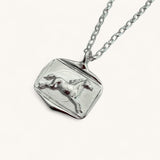 Silver pendant with horse design on a white background